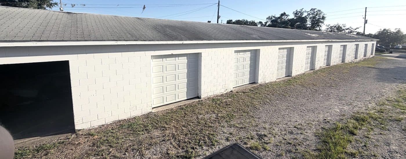 Row of white commercial roll-up doors on a self-storage building