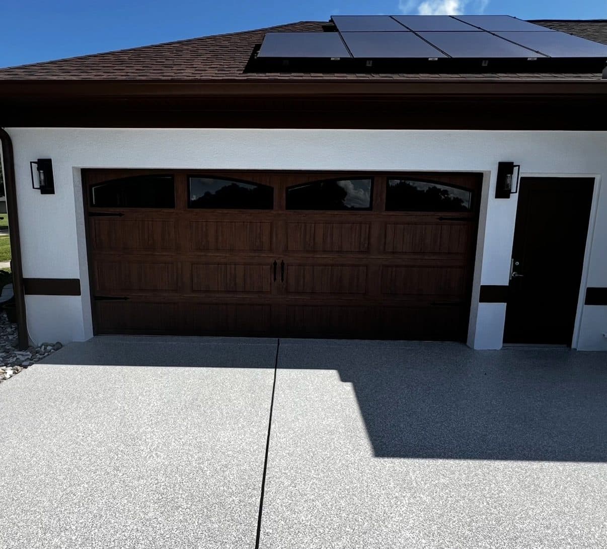 Wood-look steel garage door with windows on a modern home with solar panels